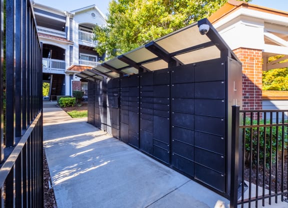 the gate to the driveway of an apartment building with a black fence
