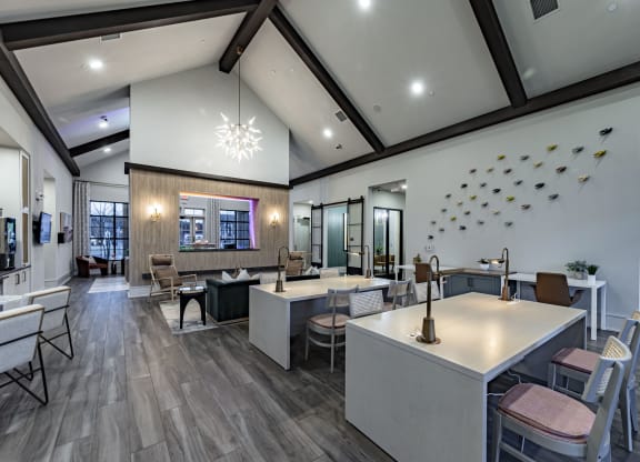 a communal dining area with tables and chairs and a kitchen with a window