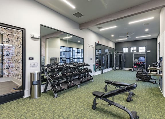 a gym with weights and mirrors and a glass door