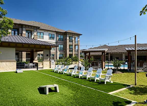 A sunny day at a resort with a row of lounge chairs and a building in the background.