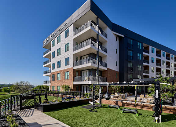 A modern apartment building with a fitness area in the front yard.