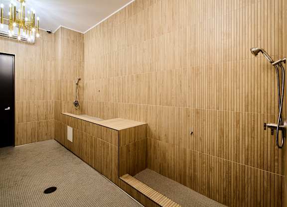 A bathroom with a wooden wall and a black door.