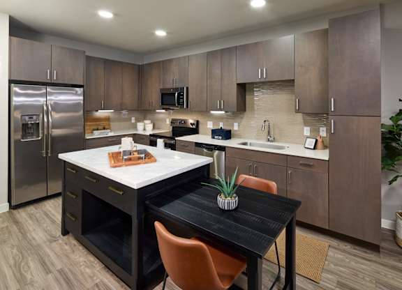 A kitchen with a table and chairs in the middle.
