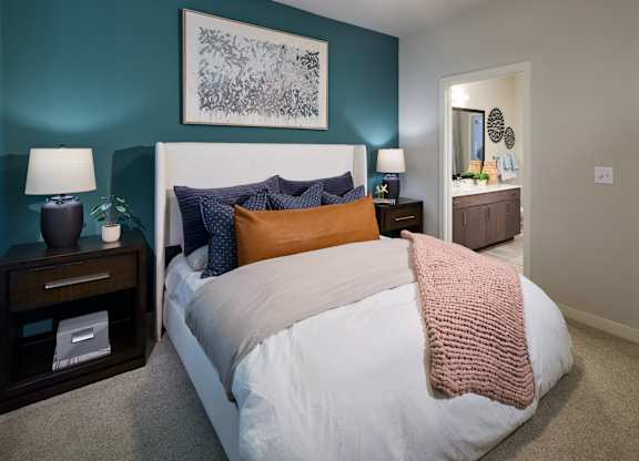 A bedroom with a white bed and a pink blanket.