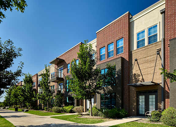 A row of apartment buildings with trees in front.