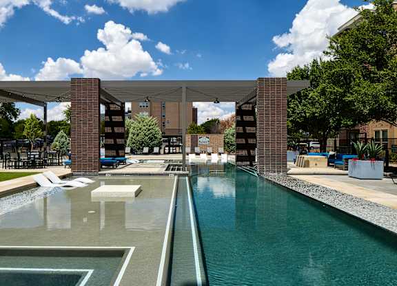 A pool with a water slide and a building in the background.