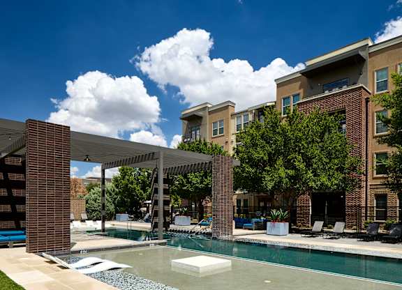 A pool area with a white umbrella and a building in the background.