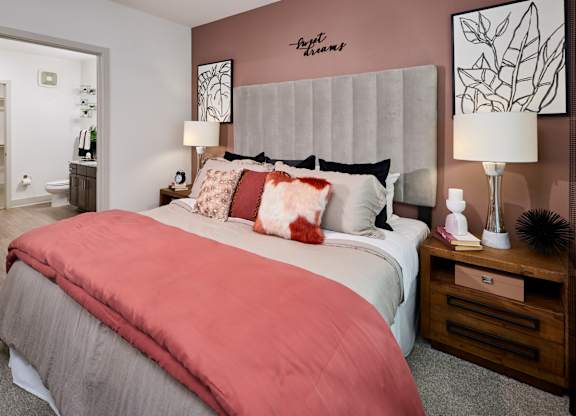 A bedroom with a bed, nightstand, and lamp.