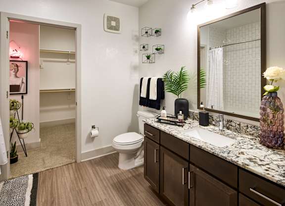A bathroom with a toilet, sink, and mirror.