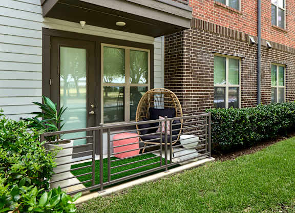 A patio with a chair and table outside a house.