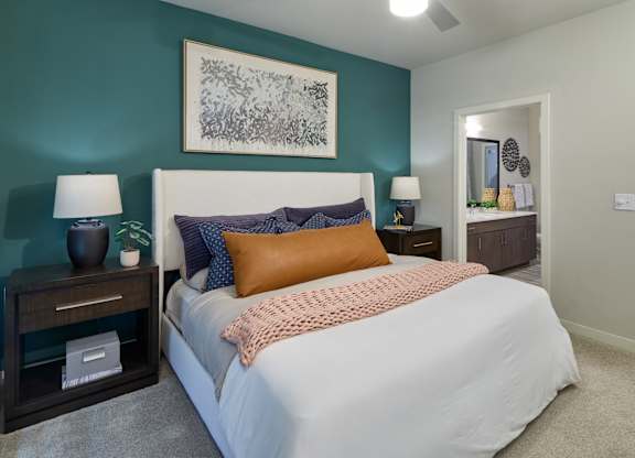 A bedroom with a bed, nightstands, and a painting on the wall.