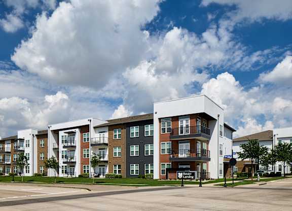A large apartment complex with a parking lot in front.
