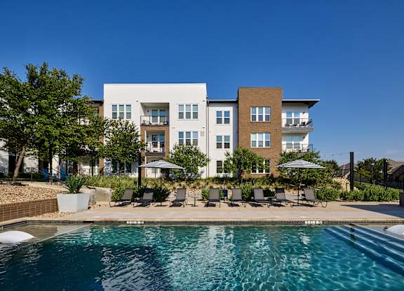 A modern apartment complex with a swimming pool in the foreground.