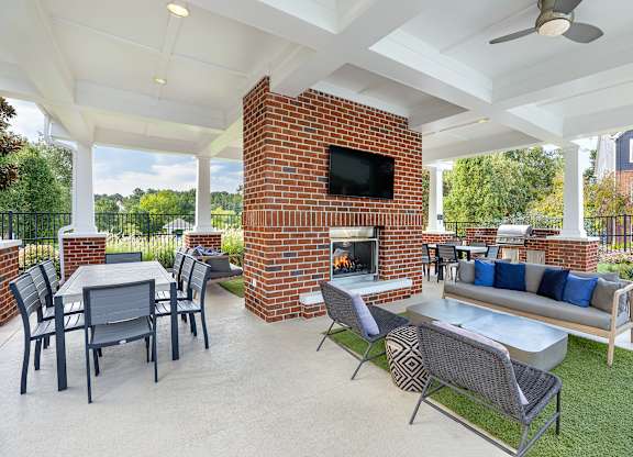 A patio with a brick fireplace and furniture.