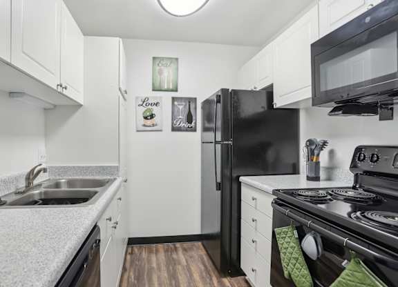 A black refrigerator sits in a kitchen with white cabinets. at Millennium at Creve Coeur, Missouri