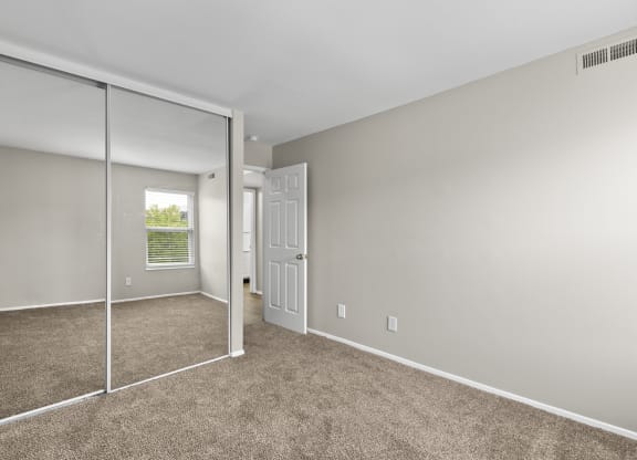 Bedroom with a mirrored closet and carpeted floors at Creve Coeur, Creve Coeur, MO
