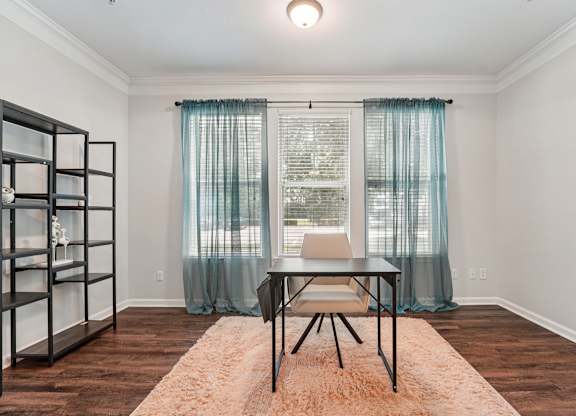 A room with a table and chairs in front of a window with curtains.