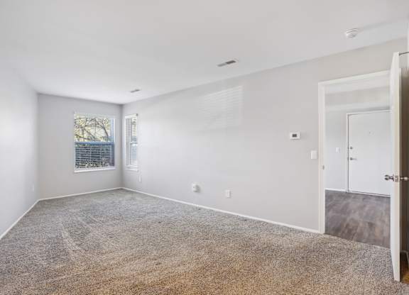 A spacious room with a carpeted floor and a door on the right side.