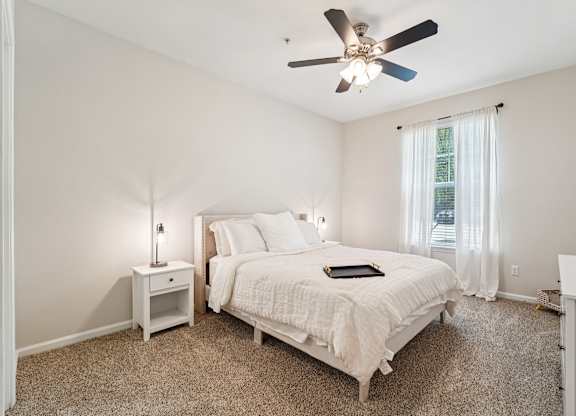 A bedroom with a bed, nightstand, and window.