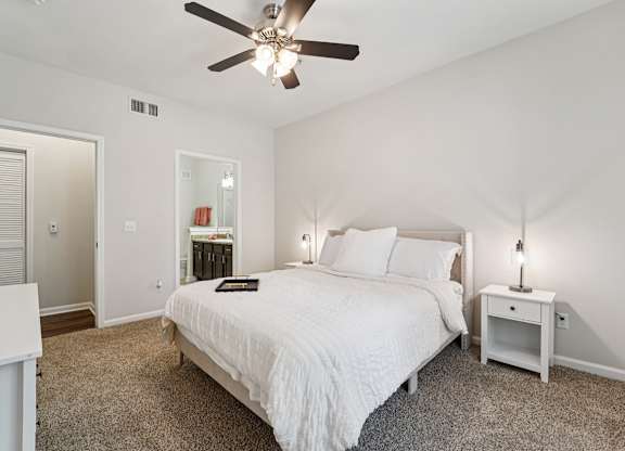 A bedroom with a bed, nightstand, and a ceiling fan.