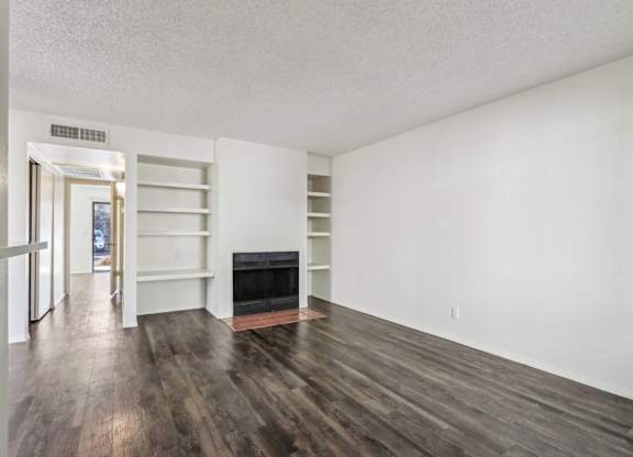 A room with a fireplace and wood flooring.