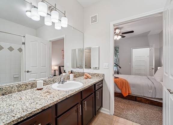 A bathroom with a marble countertop and a large mirror.