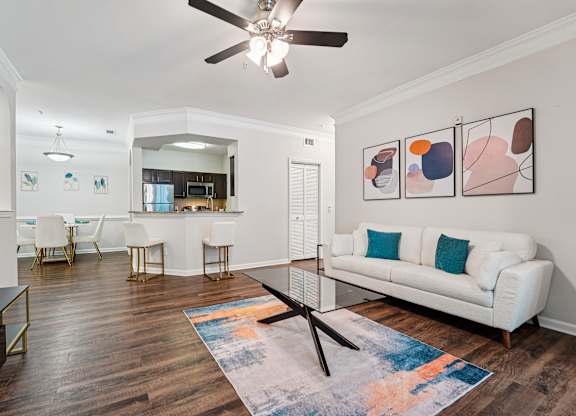 A living room with a white couch, a coffee table, and a ceiling fan.