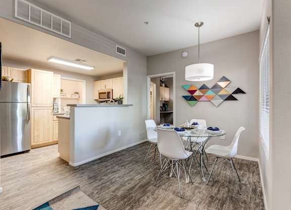 A modern kitchen with a dining table set for four at Sweetwater At Metro North Apartments, Arizona 85029