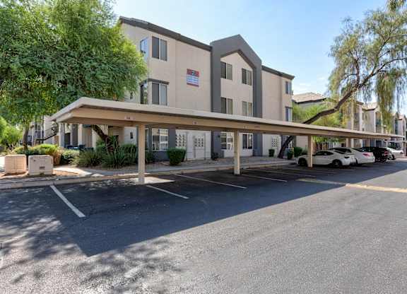 A parking lot in front of a building with a white car parked at Sweetwater At Metro North Apartments, Arizona