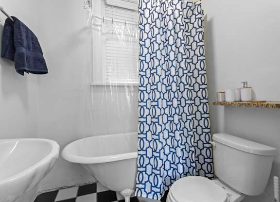 A white toilet sits next to a white sink in a bathroom with a blue and white shower curtain.