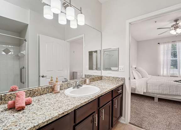 A bathroom with a sink, mirror, and bed.