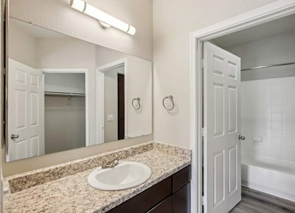 A bathroom with a sink, mirror, and bathtub at Sweetwater At Metro North Apartments, Phoenix, AZ