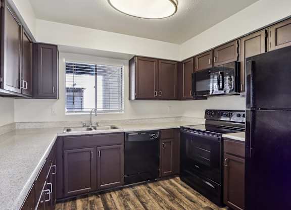 A kitchen with dark brown cabinets and black appliances.