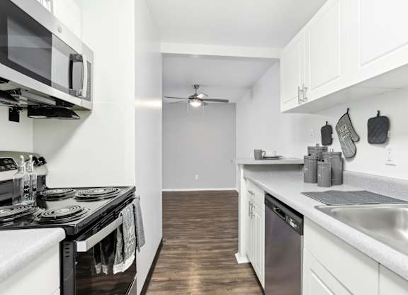 A modern kitchen with white cabinets and a black stove top.