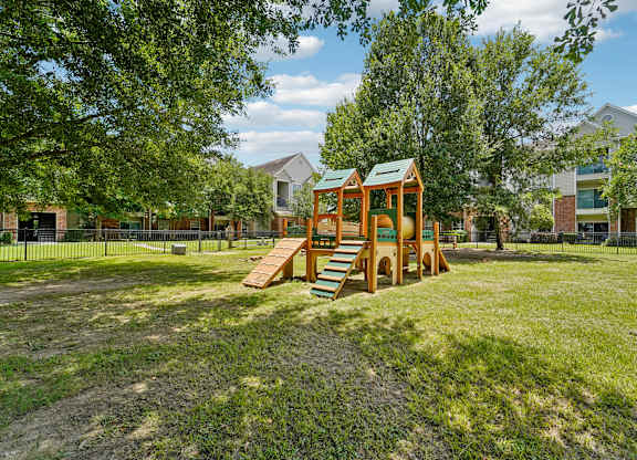 A playground with a wooden swing set and a green roof.