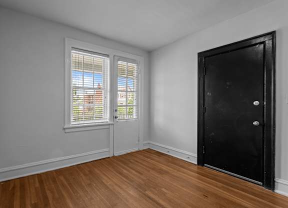 A room with a black door and a window with blinds.