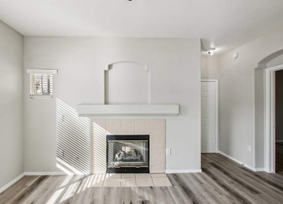 A modern living room with a fireplace and wood flooring at Sweetwater At Metro North Apartments, Phoenix, AZ 85029