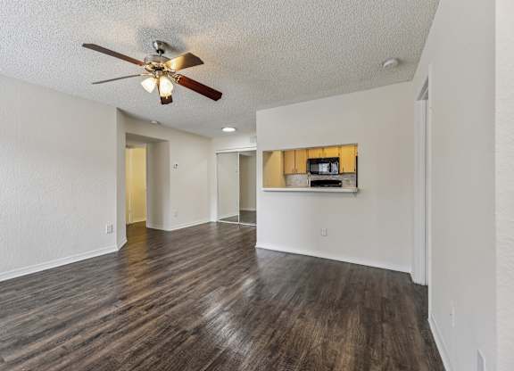 A room with a ceiling fan and wooden flooring.