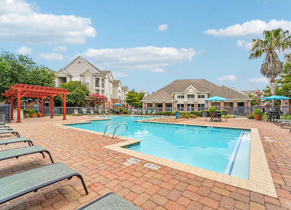 A pool surrounded by lounge chairs and umbrellas.