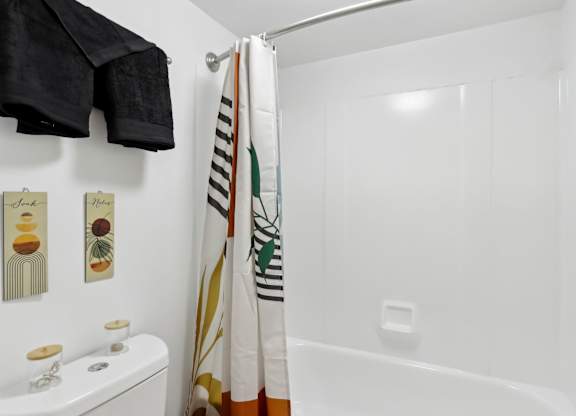 A white bathroom with a toilet, a shower curtain, and a towel rack. at Millennium at Creve Coeur, Missouri, 63141