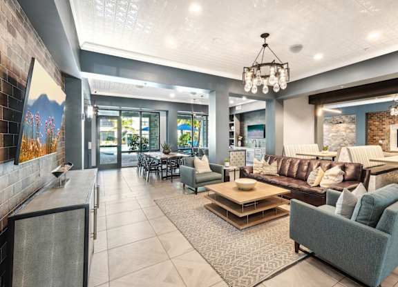 A modern living room with a grey couch and a chandelier.