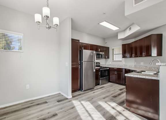 A kitchen with brown cabinets and a stainless steel refrigerator at Sweetwater At Metro North Apartments, Phoenix, Arizona