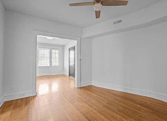 A room with a ceiling fan and wooden floors.