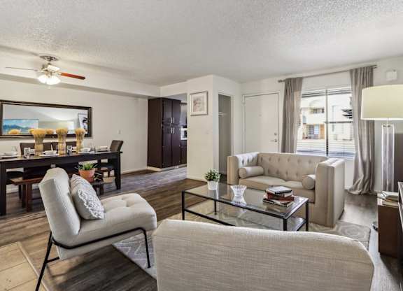 A living room with a beige couch, a glass coffee table, and a chair.