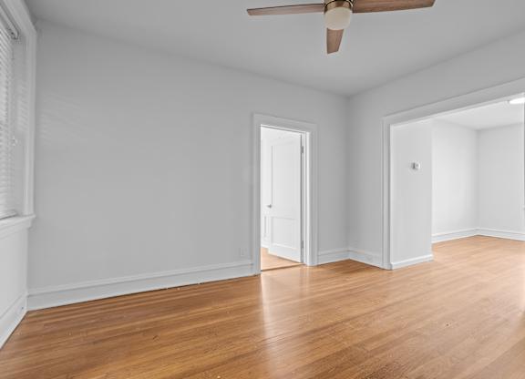A room with a ceiling fan and wooden floors.