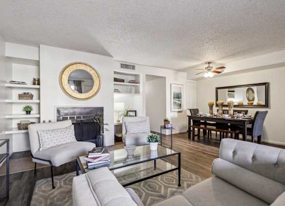 A living room with a grey couch, a glass coffee table, and a fireplace.