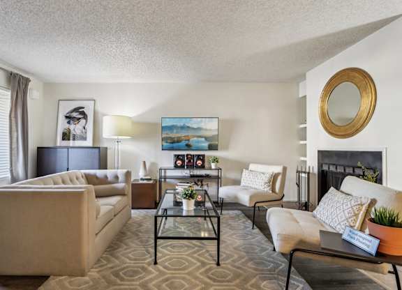 A living room with a beige sofa, a glass coffee table, and a painting on the wall.