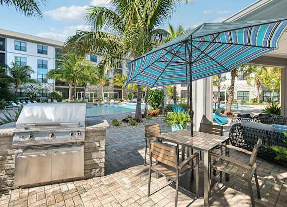 A patio with a table and chairs and a grill.