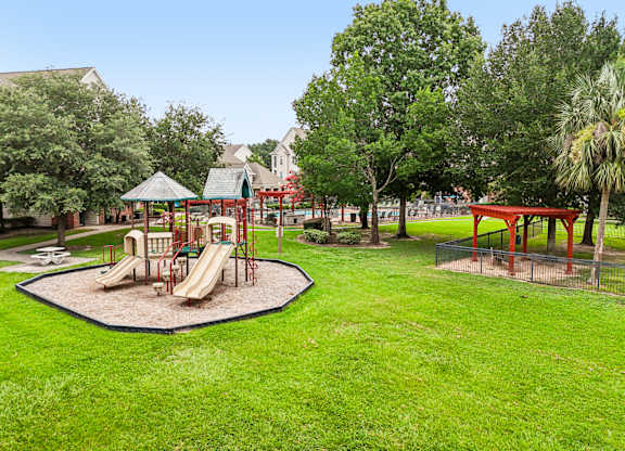 A playground with a red slide and a green lawn.