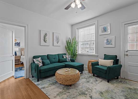 A living room with a green couch and a wicker coffee table.